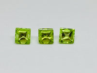 Three buff top peridot gems, white background.