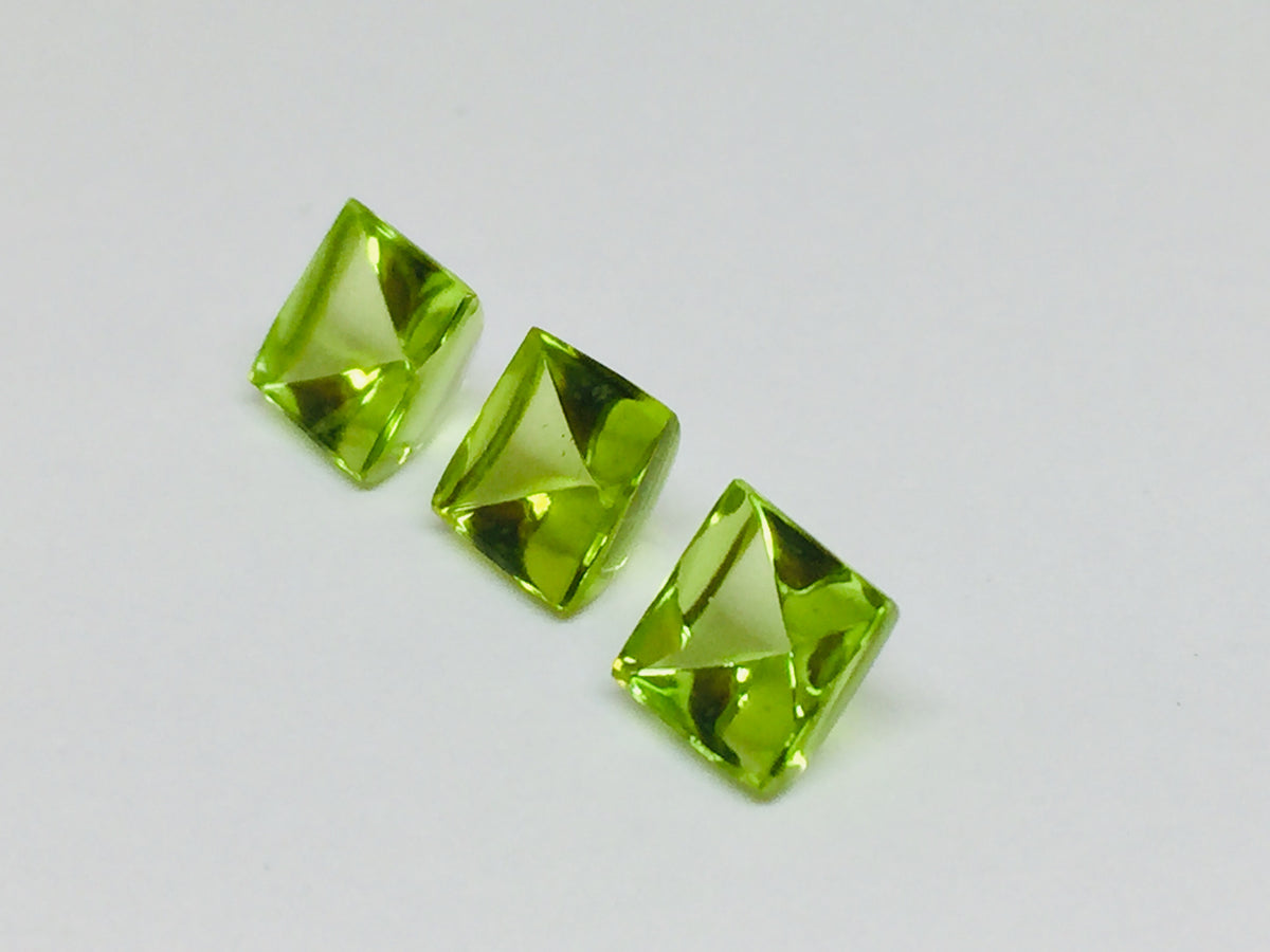 Three buff top peridot gems, white background.
