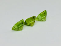 Three buff top peridot gems, white background.