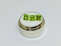 Three buff top peridot gems, white background.
