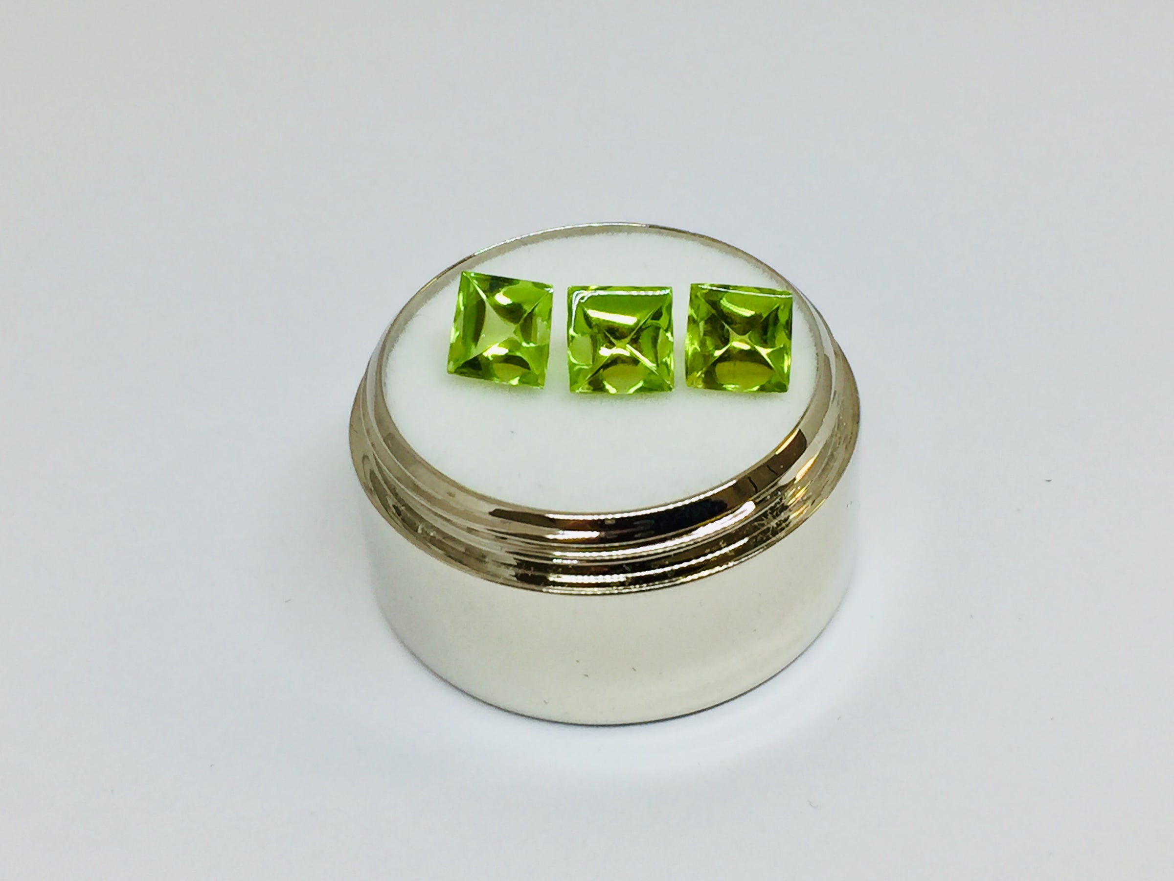 Three buff top peridot gems, white background.
