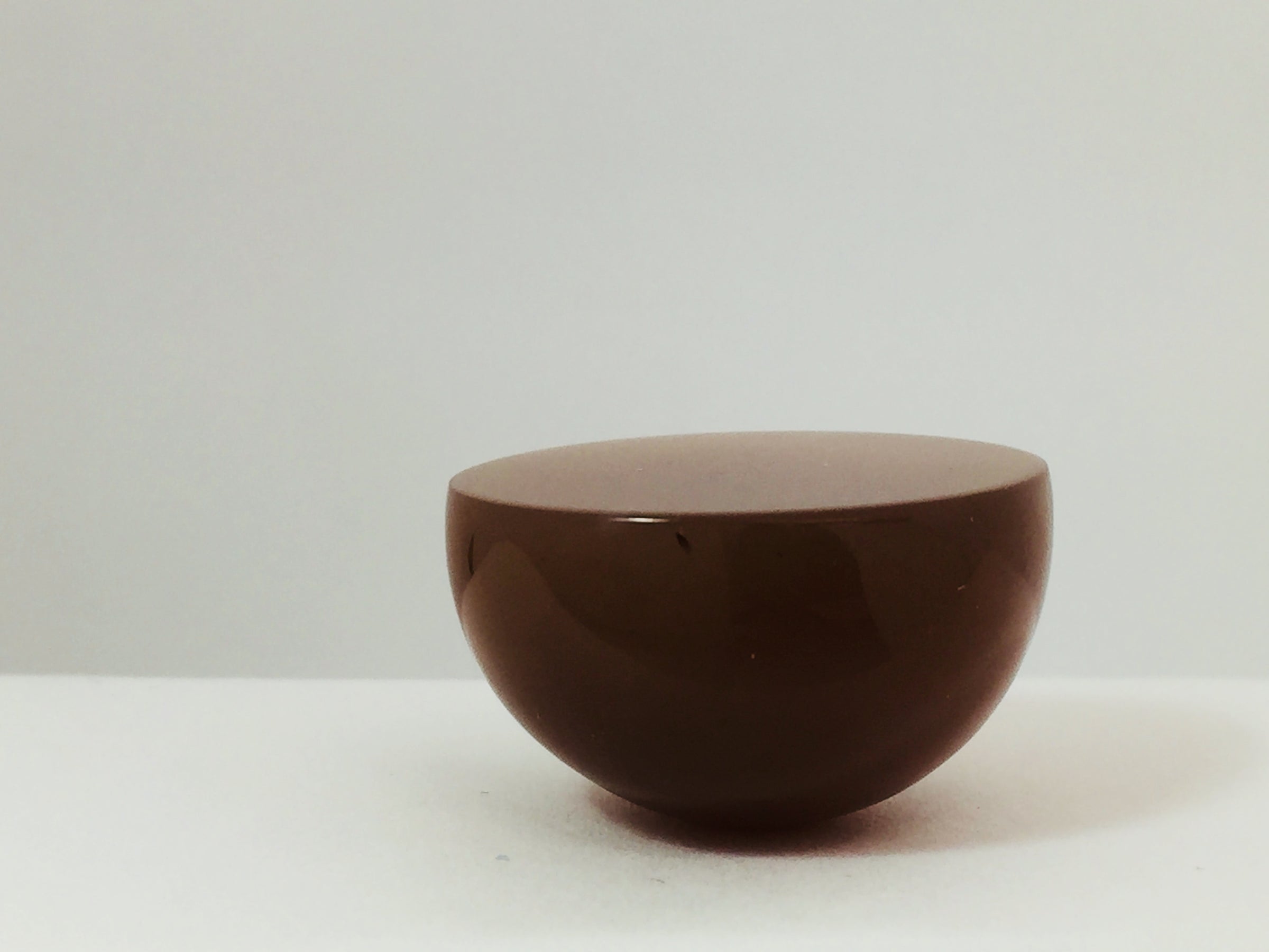 Very large round mocha coloured moonstone cabochon gem, white background.