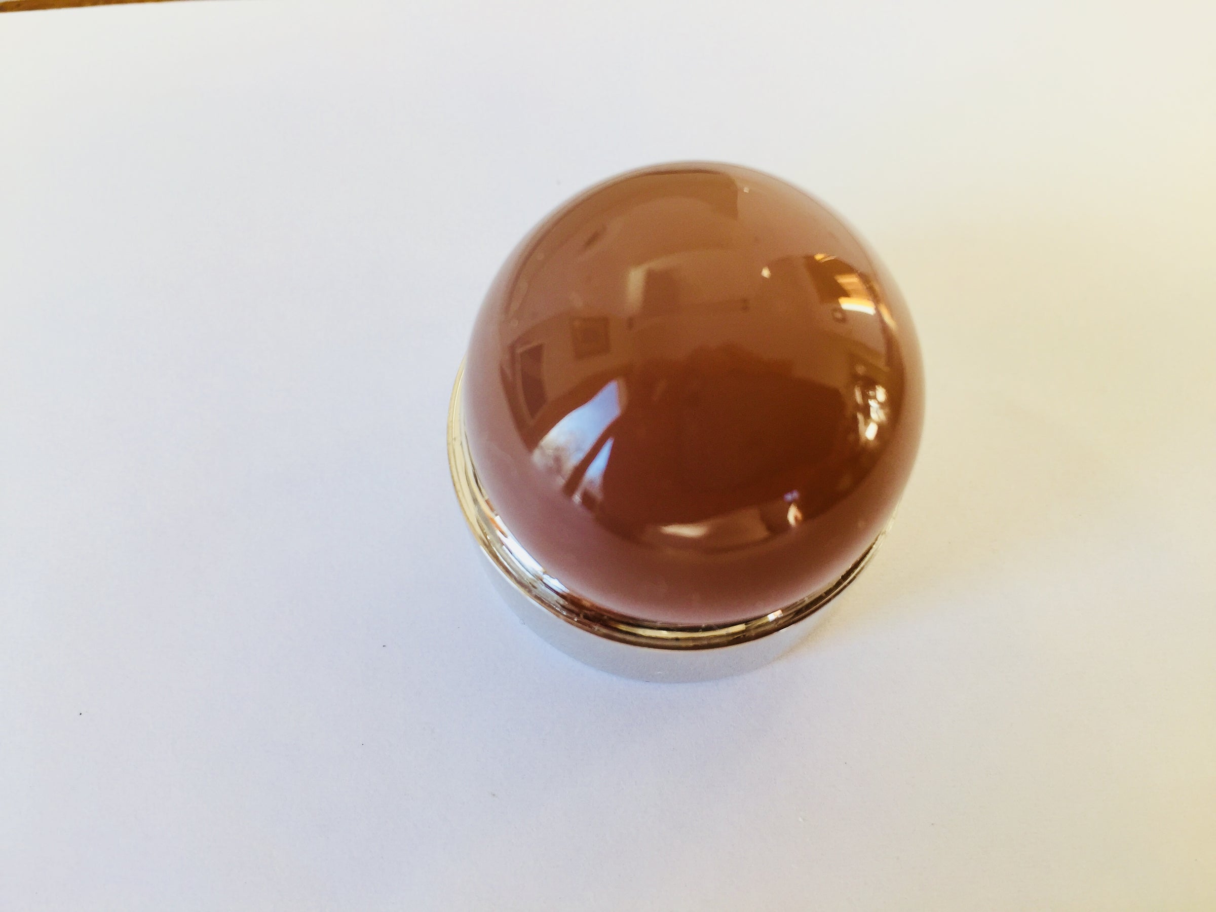 Very large round mocha coloured moonstone cabochon gem, white background in gem jar.