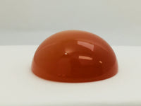Very large round orange moonstone cabochon gem, white background.