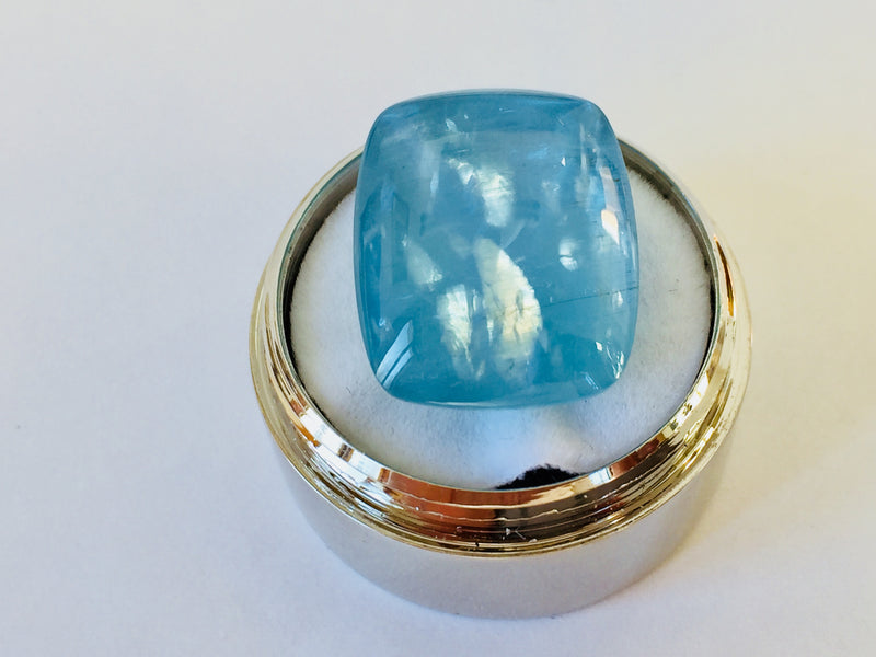 Large rectangle rich light blue aquamarine gem, white background in gem jar.