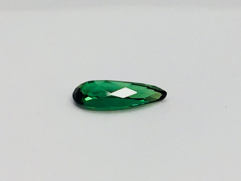 Small pear shape green tourmaline gem, white background.