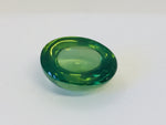 Large oval rich green zircon cabochon gem, white background.