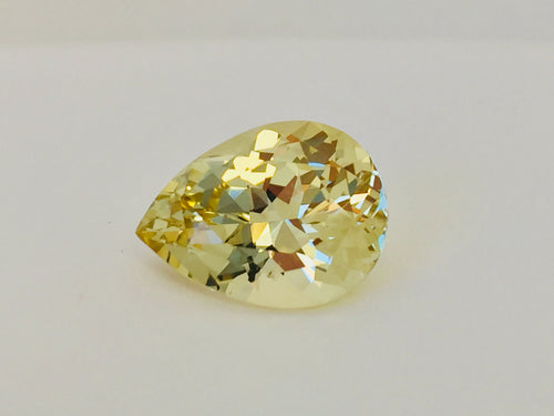 Large pear shaped light yellow chrysoberyl gem, on white background.