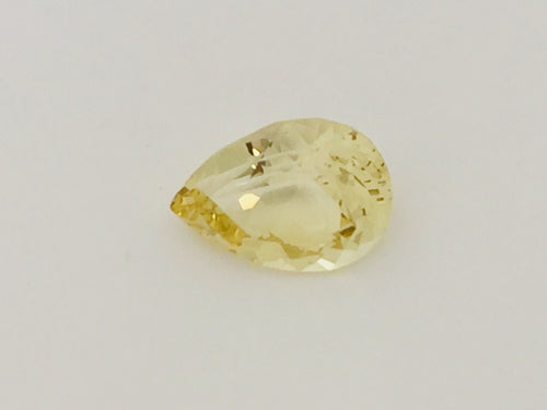 Large pear shaped light yellow chrysoberyl gem, on white background.