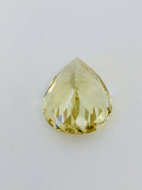 Large pear shaped light yellow chrysoberyl gem, on white background.