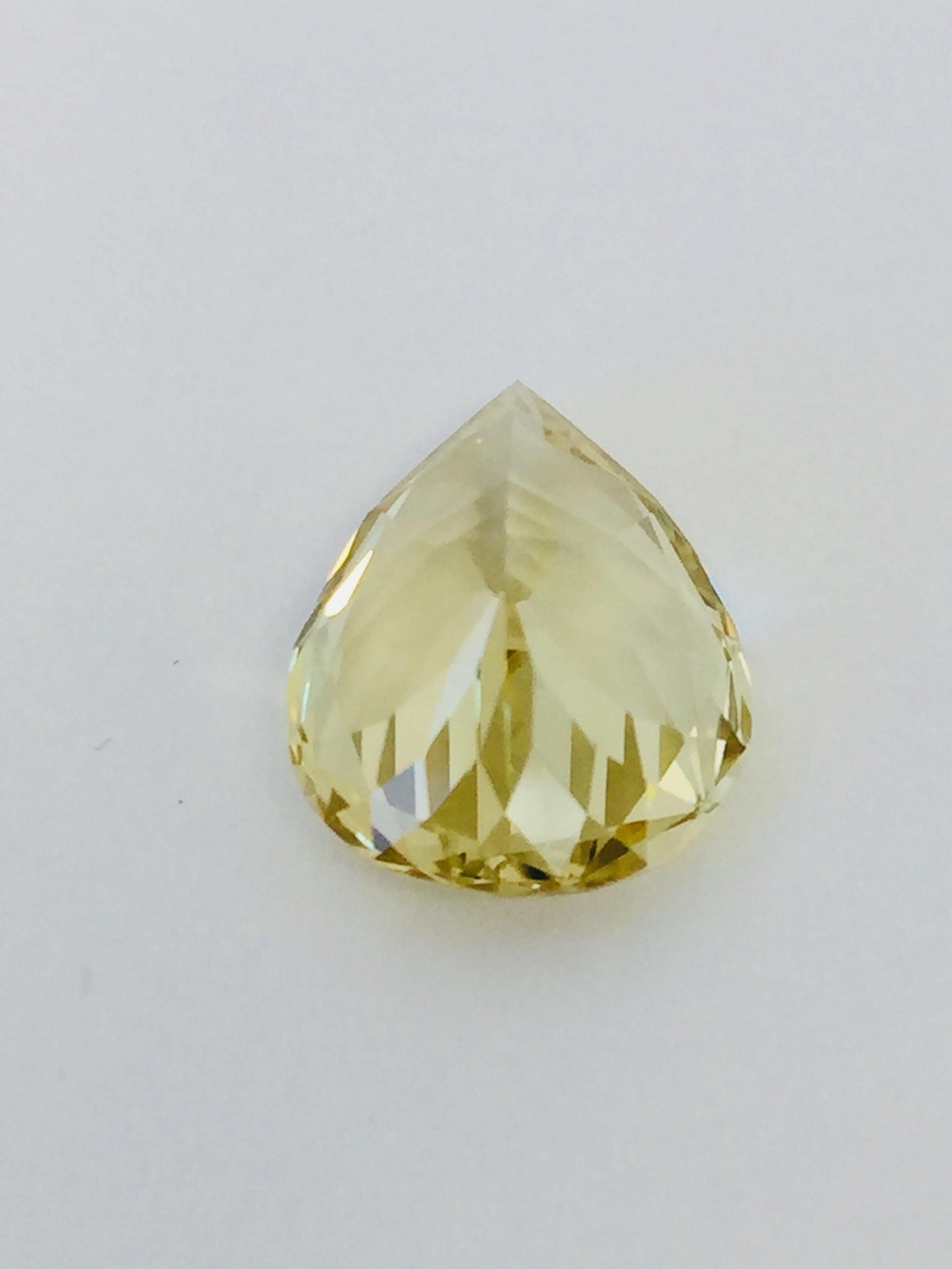 Large pear shaped light yellow chrysoberyl gem, on white background.
