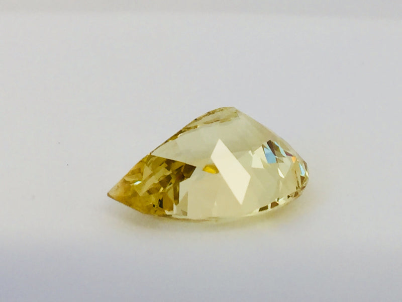 Large pear shaped light yellow chrysoberyl gem, on white background.