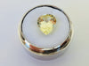 Large pear shaped light yellow chrysoberyl gem, on white background in gem jar.