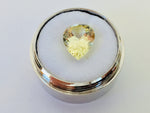 Large pear shaped light yellow chrysoberyl gem, on white background in gem jar.