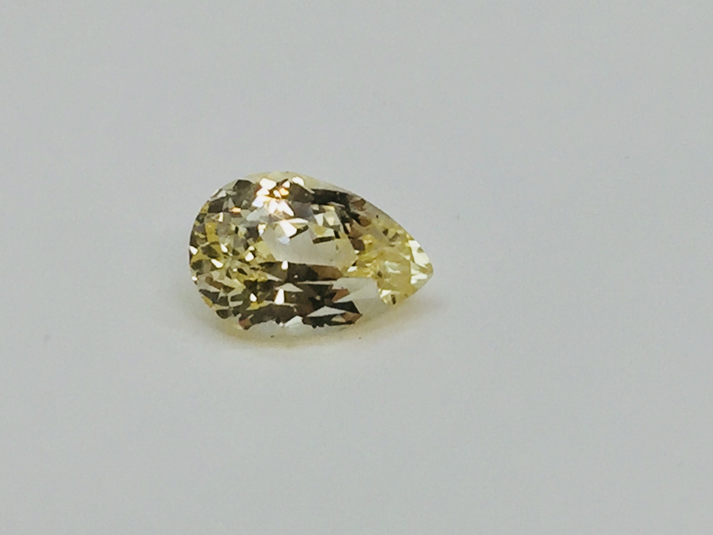 Large pear-shaped green-yellow chrysoberyl gem, white background.