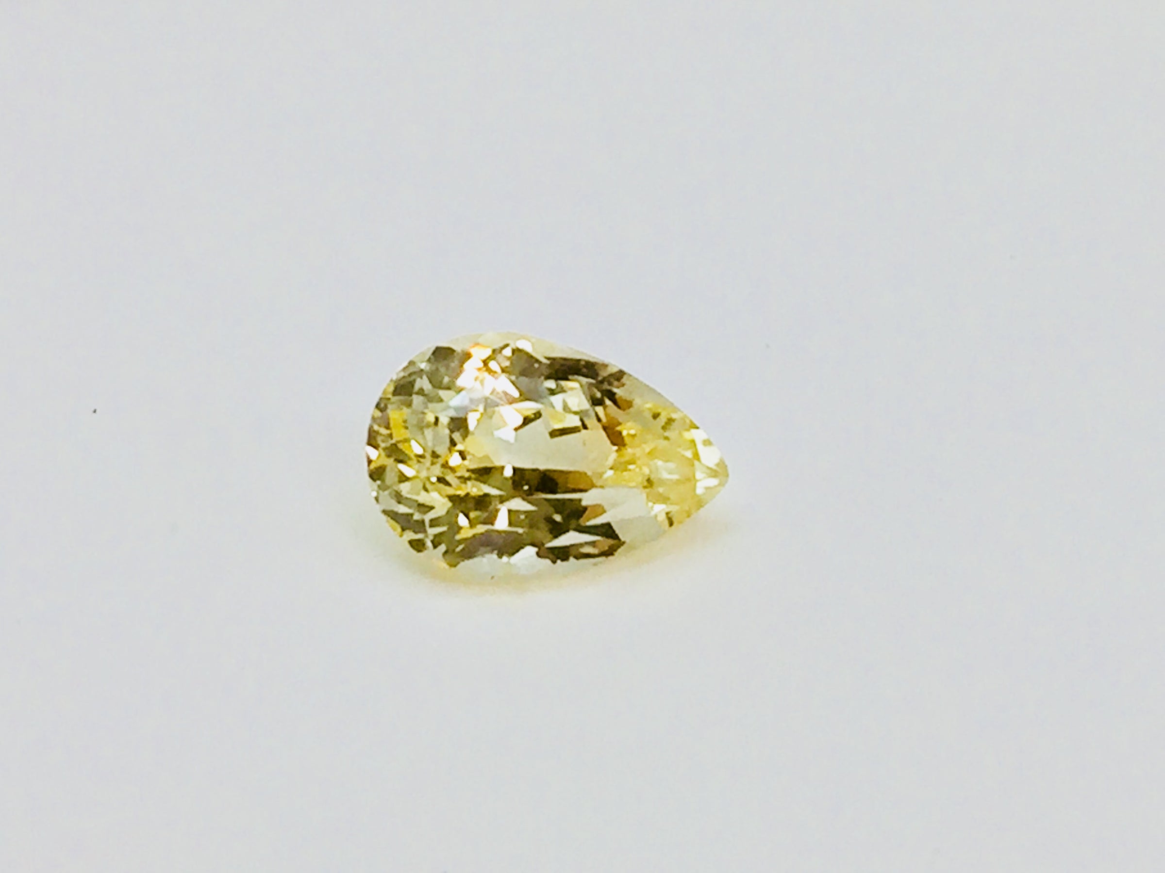 Medium pear-shaped yellow sapphire gem, white background.