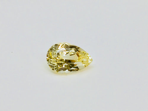 Medium pear-shaped yellow sapphire gem, white background.
