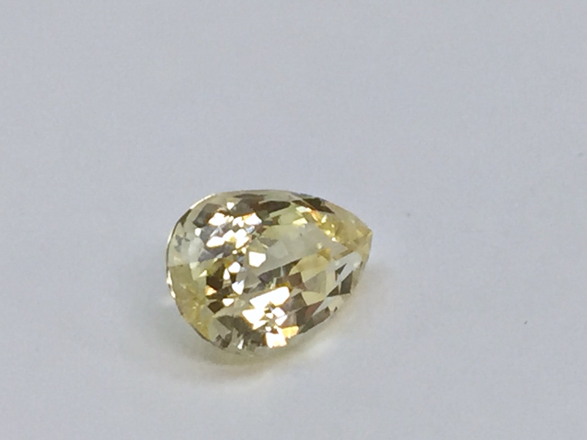 Medium pear-shaped yellow sapphire gem, white background.