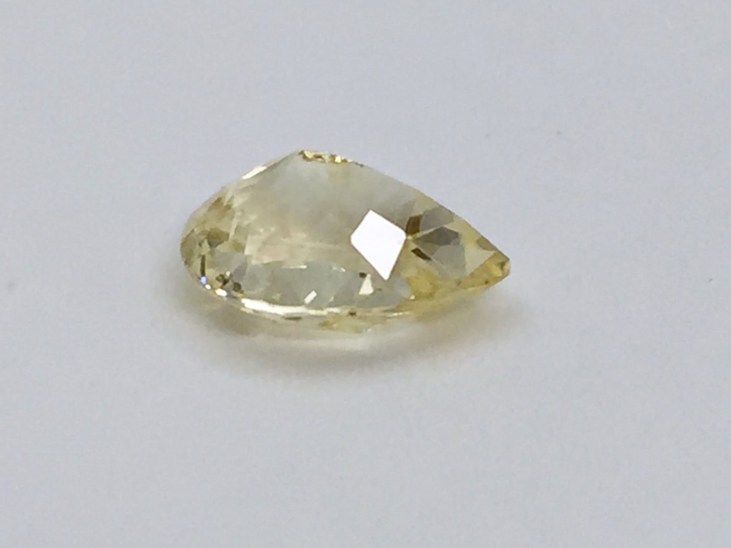 Medium pear-shaped yellow sapphire gem, white background.