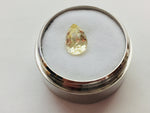 Medium pear-shaped yellow sapphire gem, white background in gem jar.