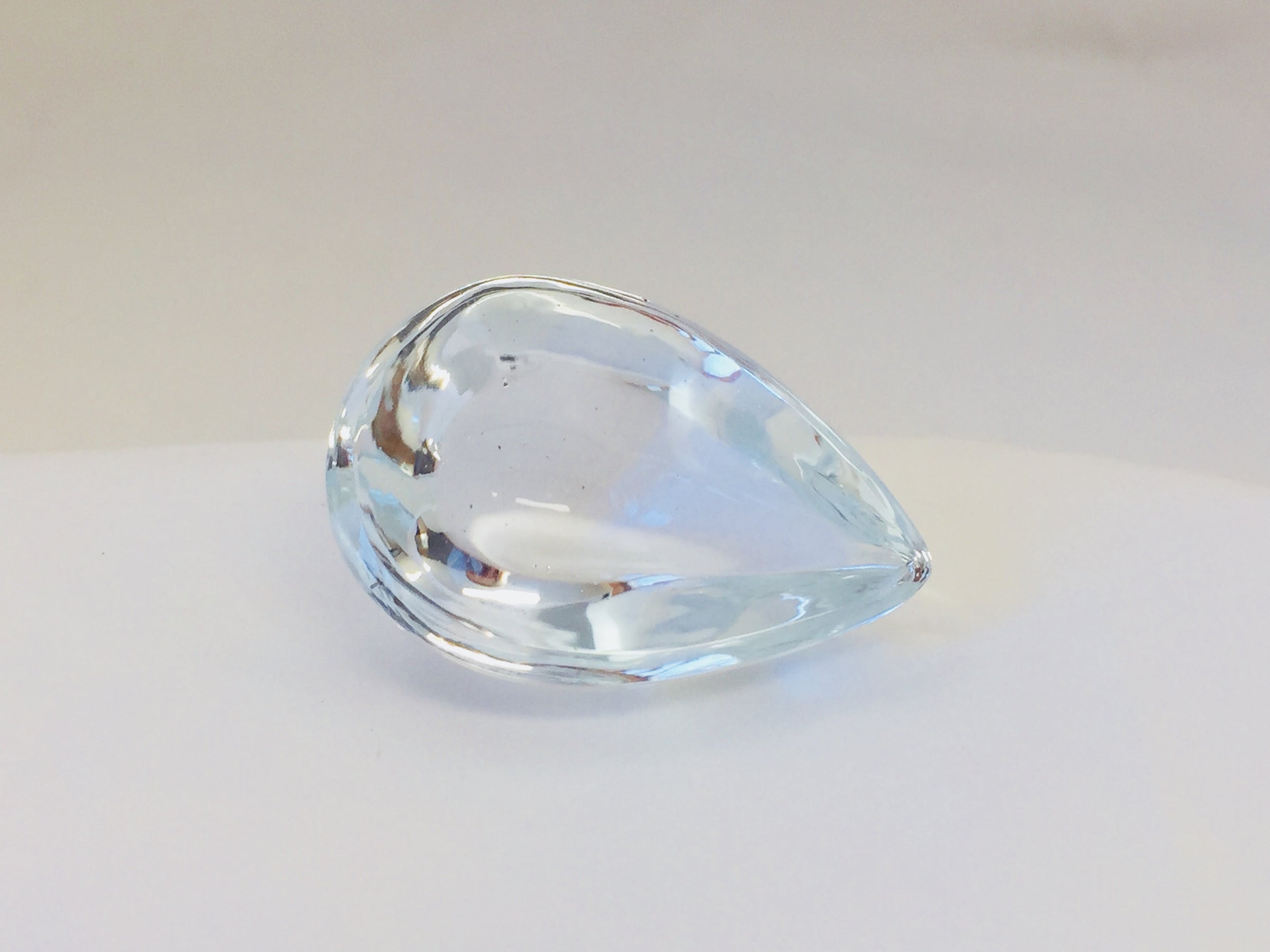 Very large colourless tear-drop shape white topaz gem, white backgroound.