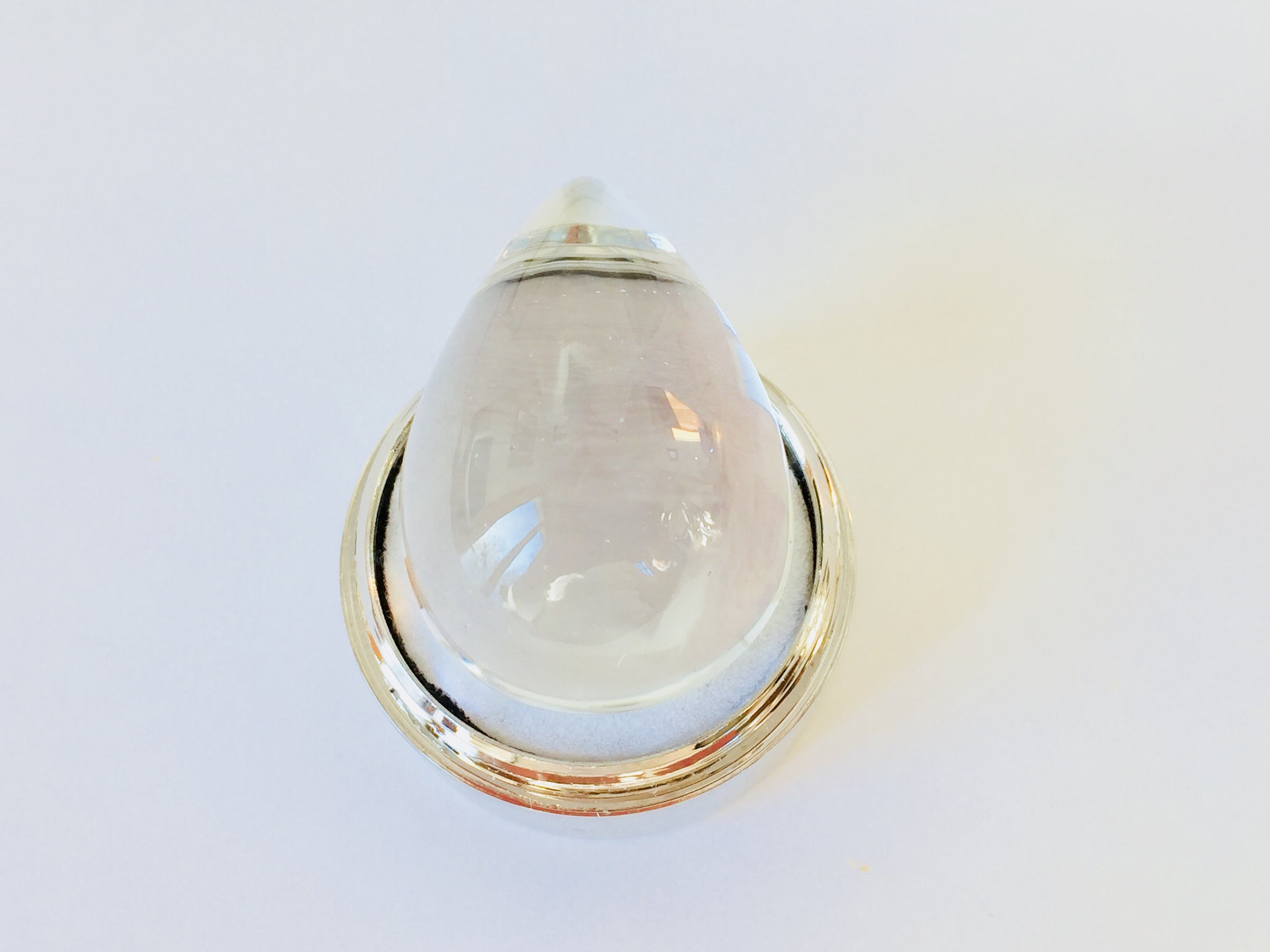 Very large colourless tear-drop shape white topaz gem, white background in gem jar.