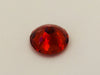 Medium round deep orange spessartite garnet gem, white background.