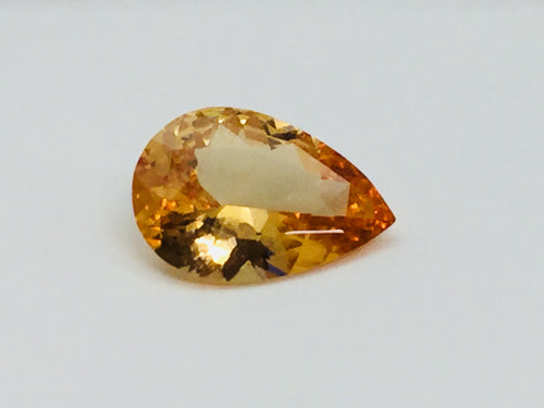 Large pear shaped orange hessonite garnet gem, on white background.