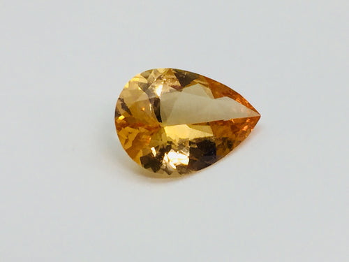 Large pear shaped orange hessonite garnet gem, on white background.