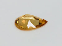 Large pear shaped orange hessonite garnet gem, on white background.