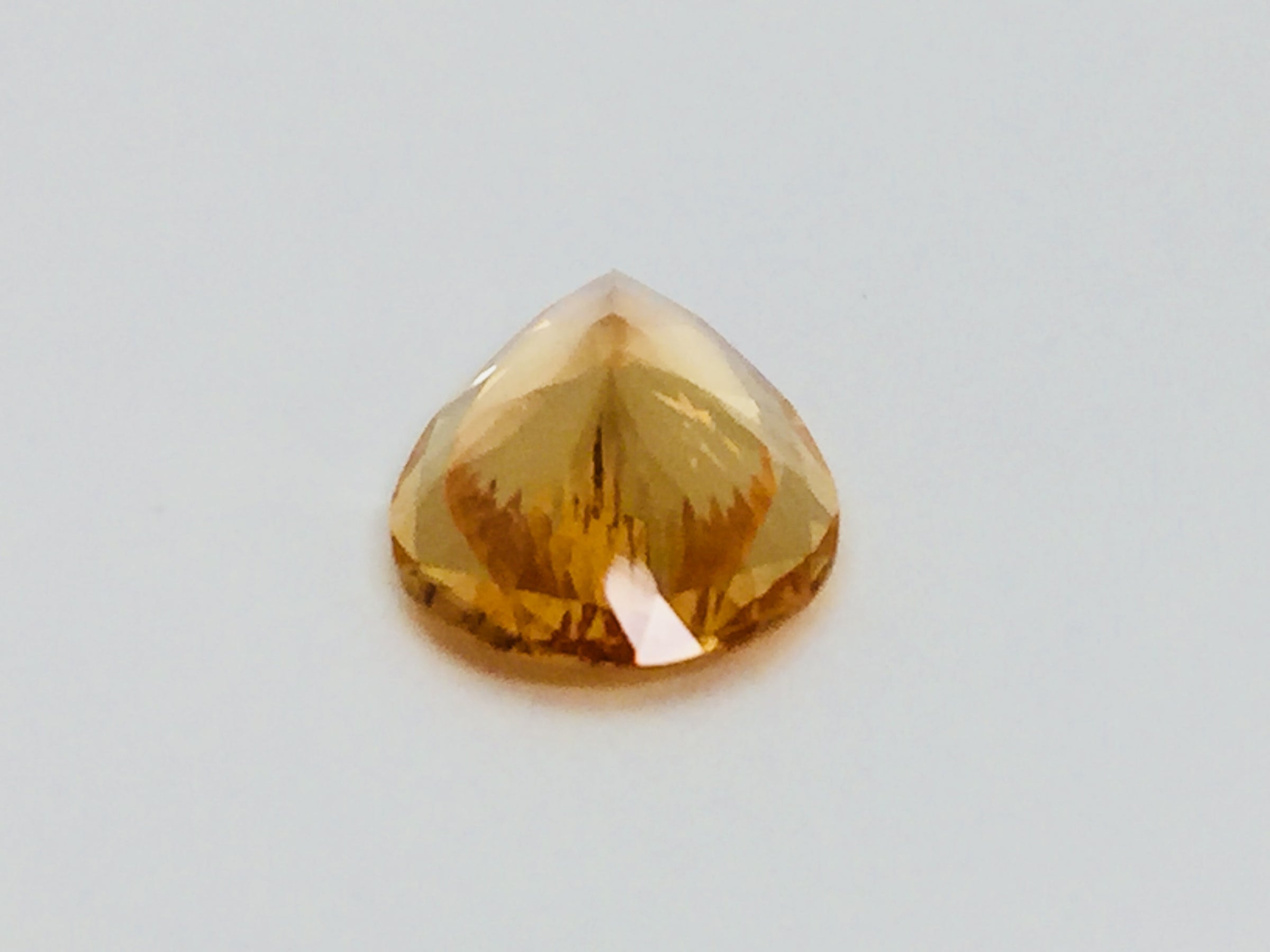 Large pear shaped orange hessonite garnet gem, on white background.