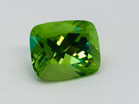 Large deep green cushion shaped peridot gem, white background.
