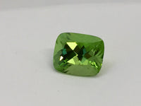 Large deep green cushion shaped peridot gem, white background.