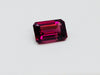 Medium size rectangular deep purple rhodolite garnet gem, on white background.