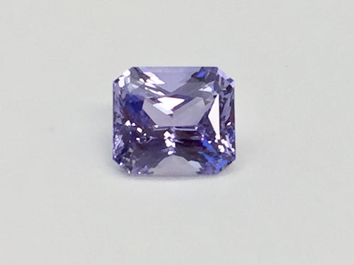 Violet coloured sapphire gem, white background.