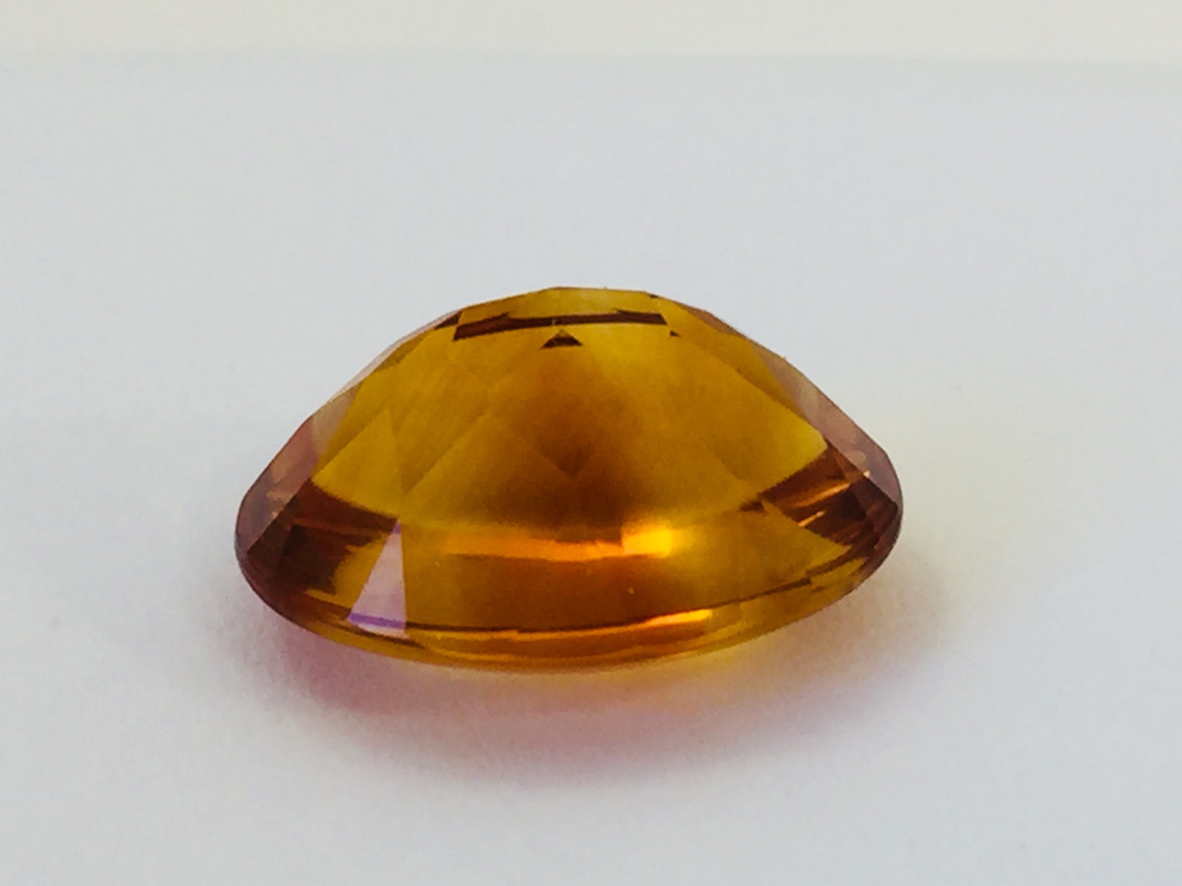 Large oval deep orange citrine gem, on white background.