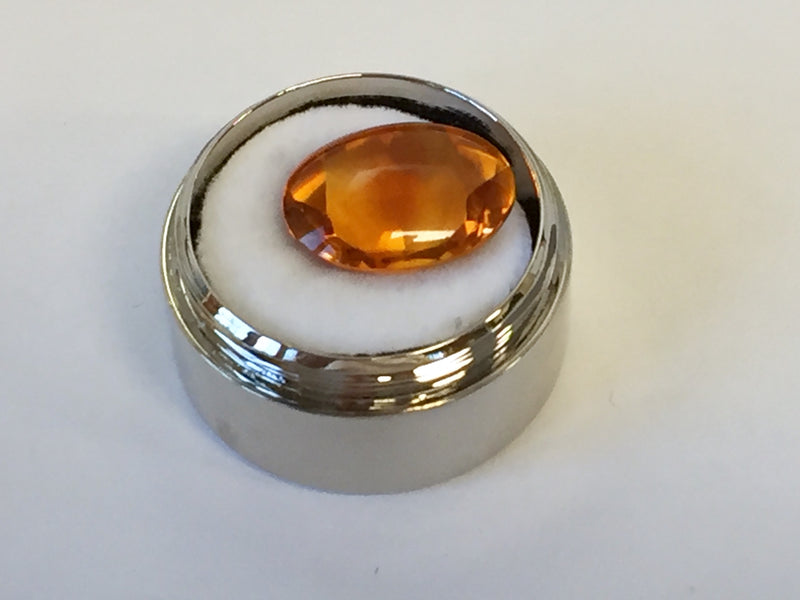 Large oval deep orange citrine gem, on white background in gem jar.