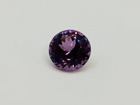 Medium round deep purple spinel gem, on white background.