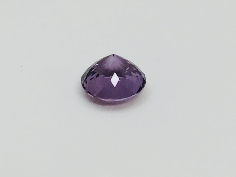 Medium round deep purple spinel gem, on white background.
