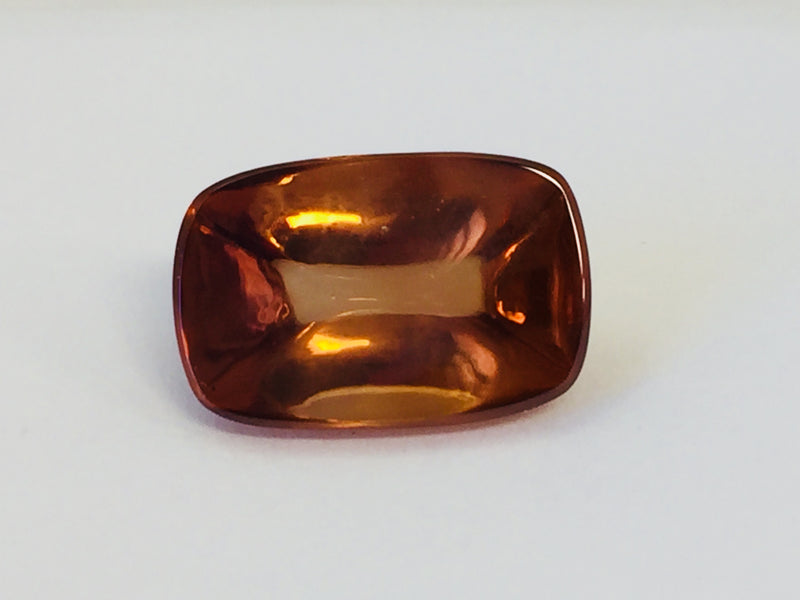 Rectangular deep golden brown cabochon zircon gem, on white background.