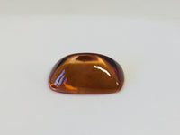 Rectangular deep golden brown cabochon zircon gem, on white background.