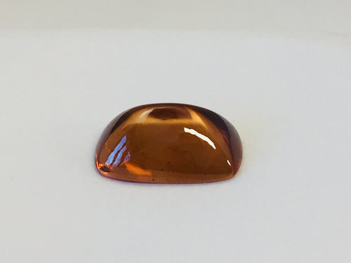 Rectangular deep golden brown cabochon zircon gem, on white background.