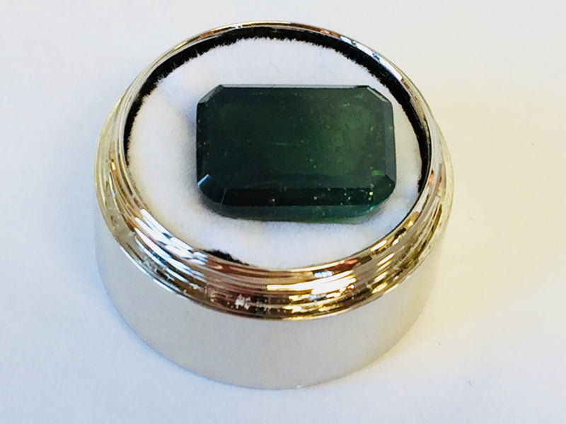 Large rectangle green tourmaline zircon gem, white background, in gem jar.