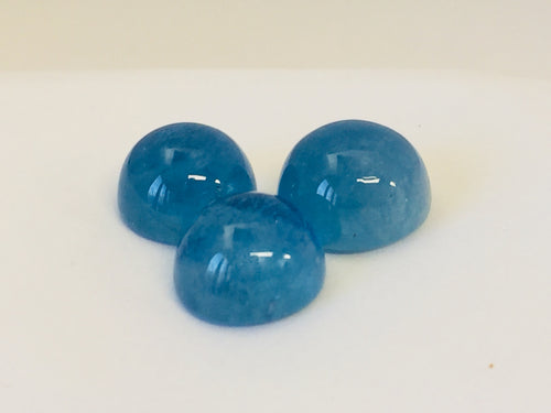 Three medium round medium blue cabochon aquamarine gems, white background.