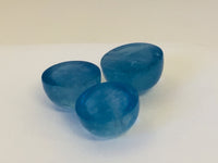 Three medium round medium blue cabochon aquamarine gems, white background.
