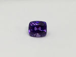 Deep purple coloured sapphire gem, white background.