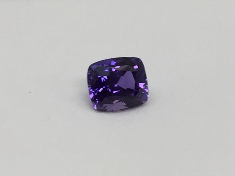 Deep purple coloured sapphire gem, white background.
