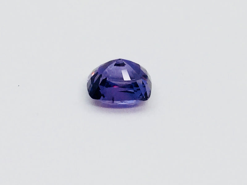 Deep purple coloured sapphire gem, white background.