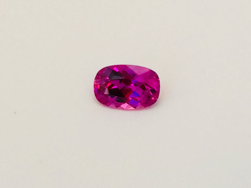 Small rectangle vivid pink sapphire gem, white background.