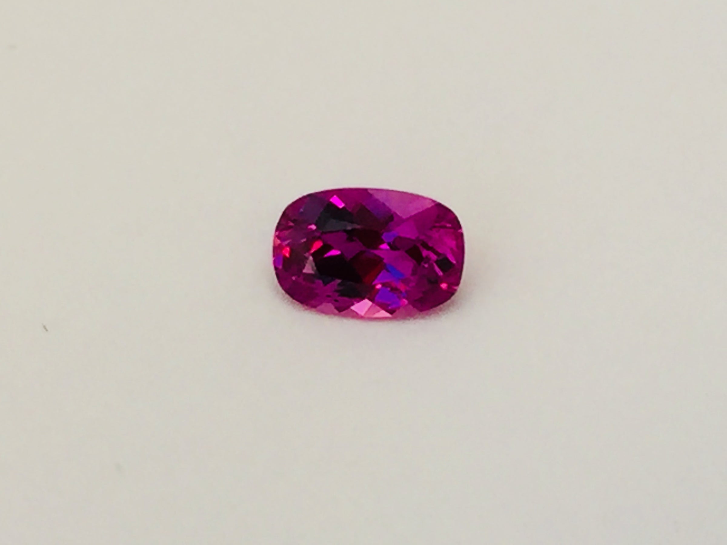 Small rectangle vivid pink sapphire gem, white background.